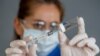 COVID-19 Coronavirus Vaccine. Doctor scientist with syringe analyzing virus Sars-CoV-2 in research for the vaccine.